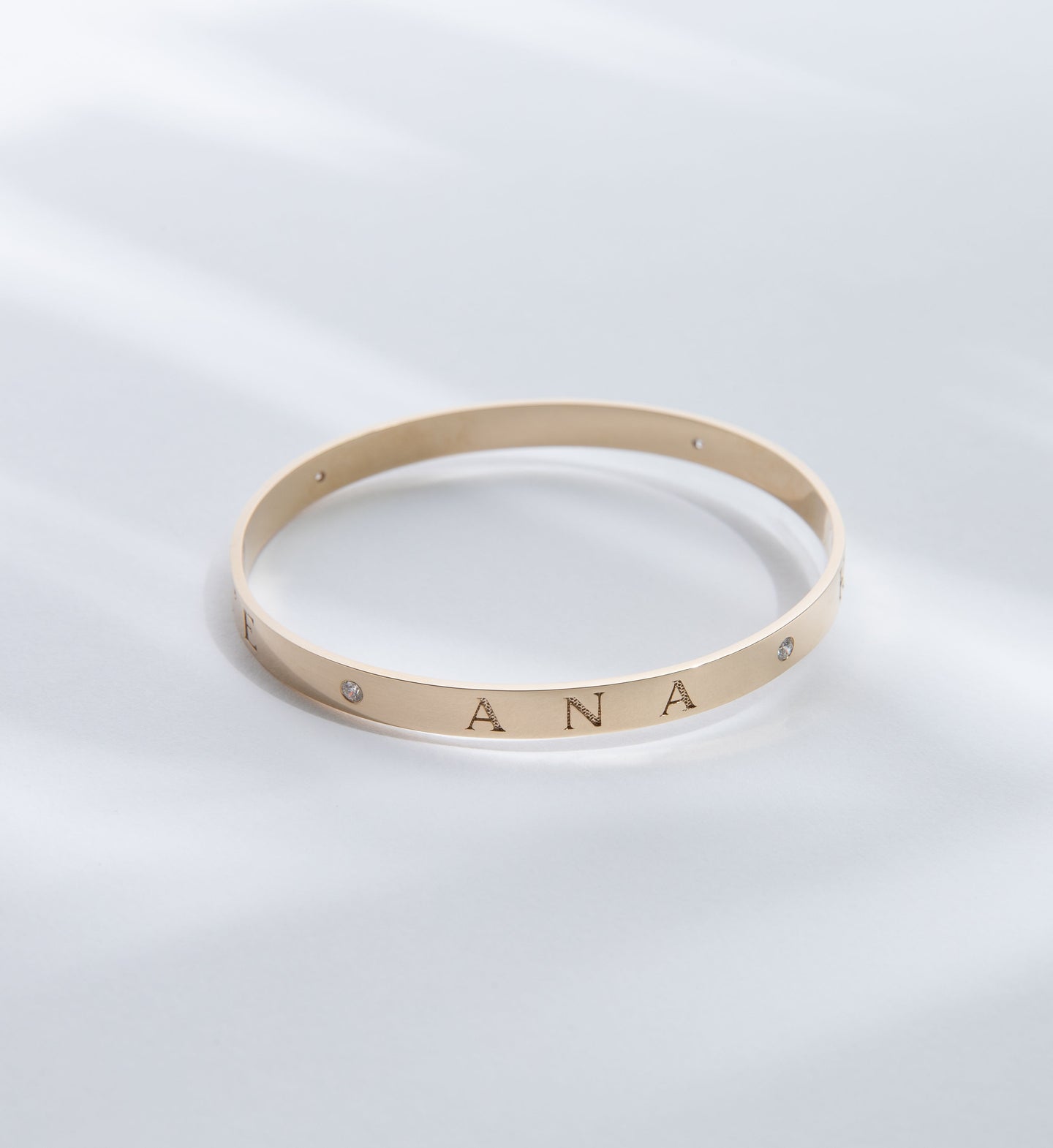 Hie Aloha Nui bangle bracelet in gold, engraved with the name Ana and including diamond accents