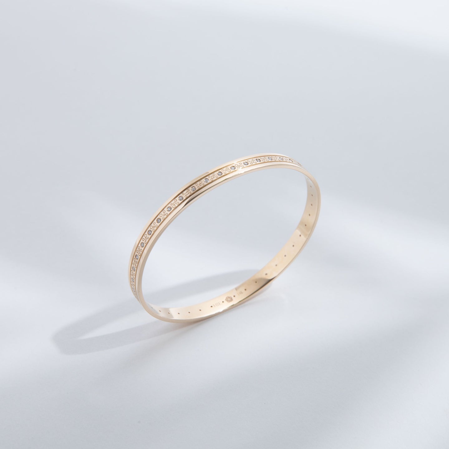 Hie Tutu Leslie gold bangle bracelet with engraved pattern and diamonds, standing upright