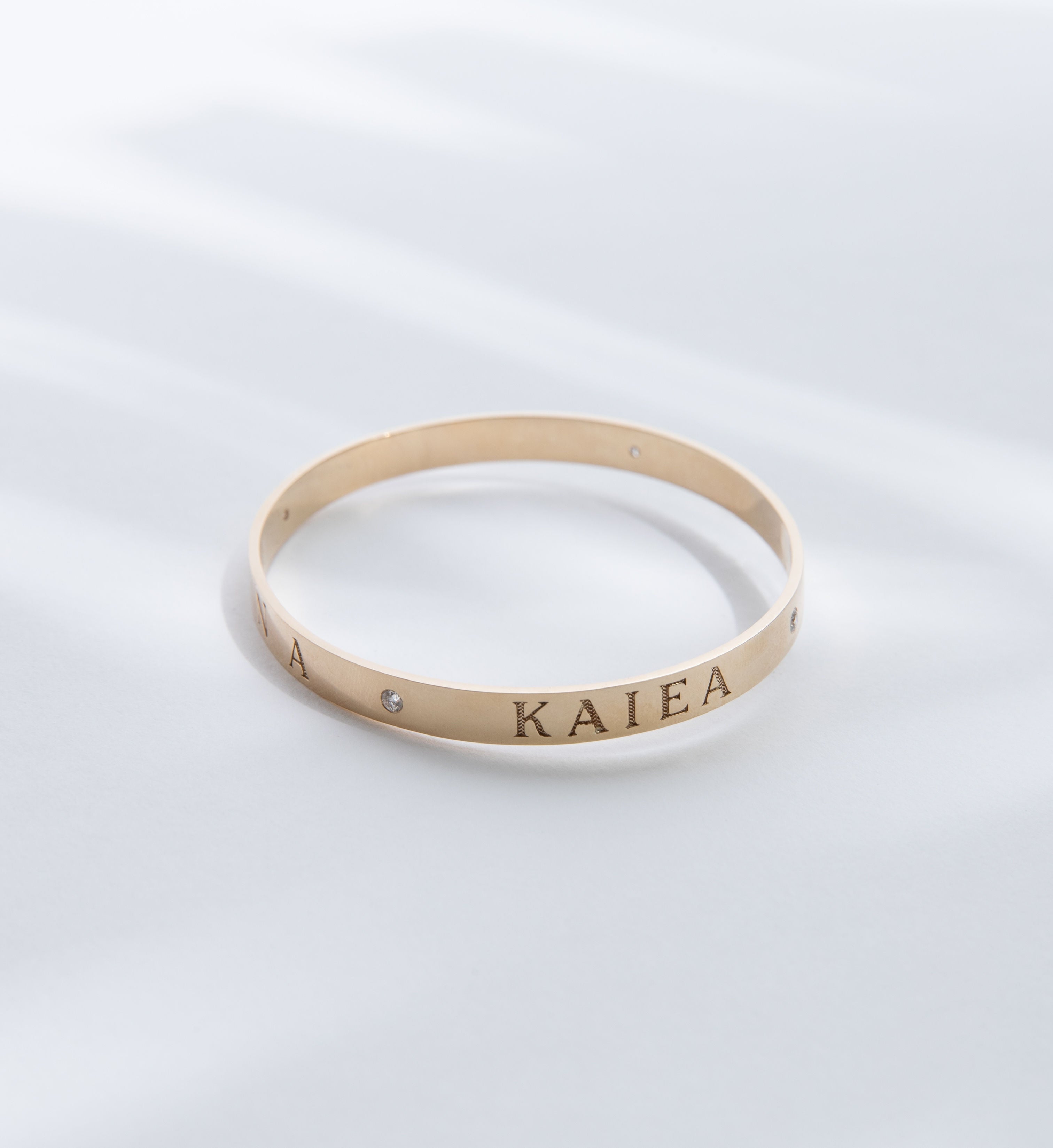 Hie Aloha Nui bangle bracelet in gold, engraved with the name Kaiea and including diamond accents