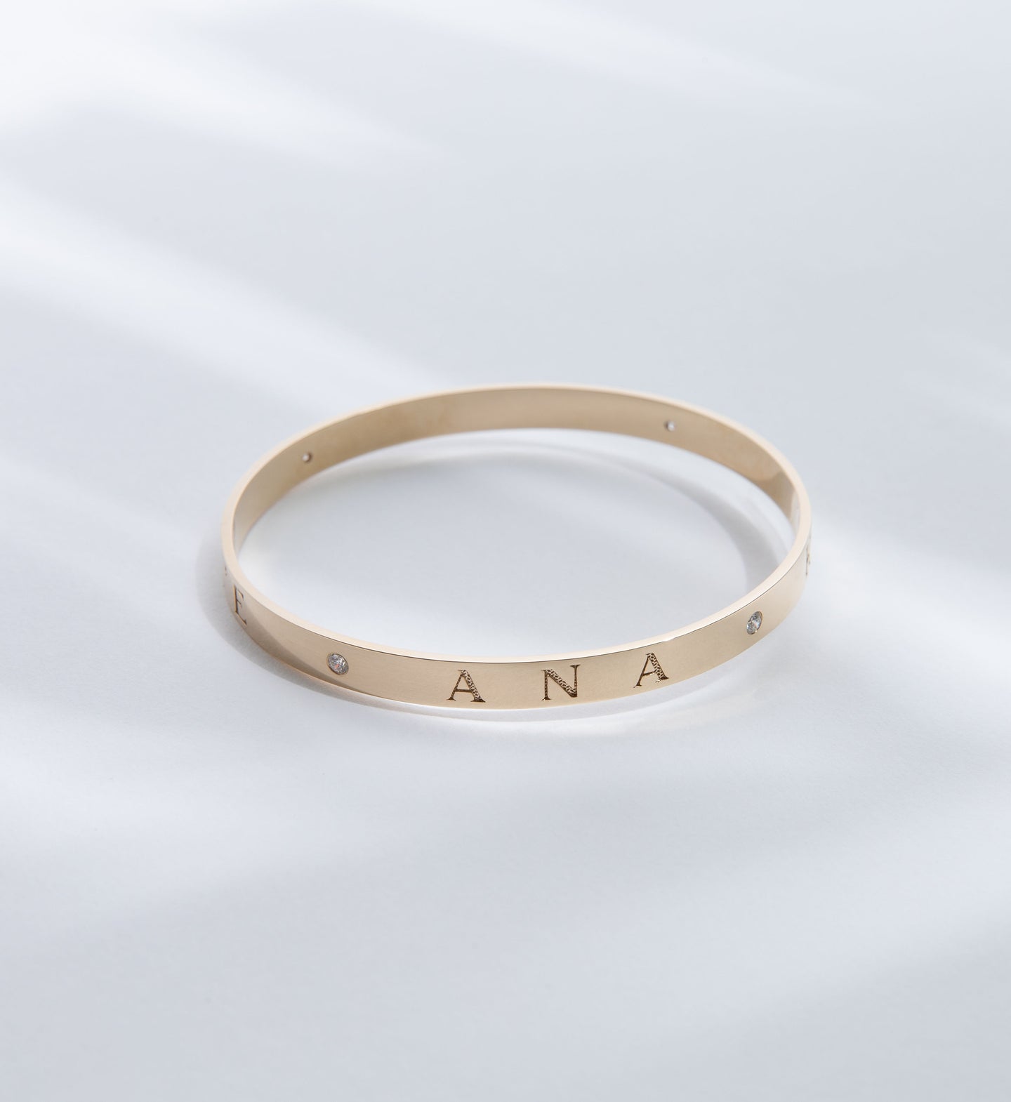 Hie Aloha Nui bangle bracelet in gold, engraved with the name Ana and including diamond accents