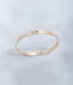 Hie Signature bangle bracelet in gold with logo engraving, standing upright