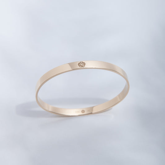 Hie Signature bangle bracelet in gold with logo engraving, standing upright