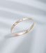 Hie Signature bangle bracelet in gold with logo engraving and diamond details, standing upright