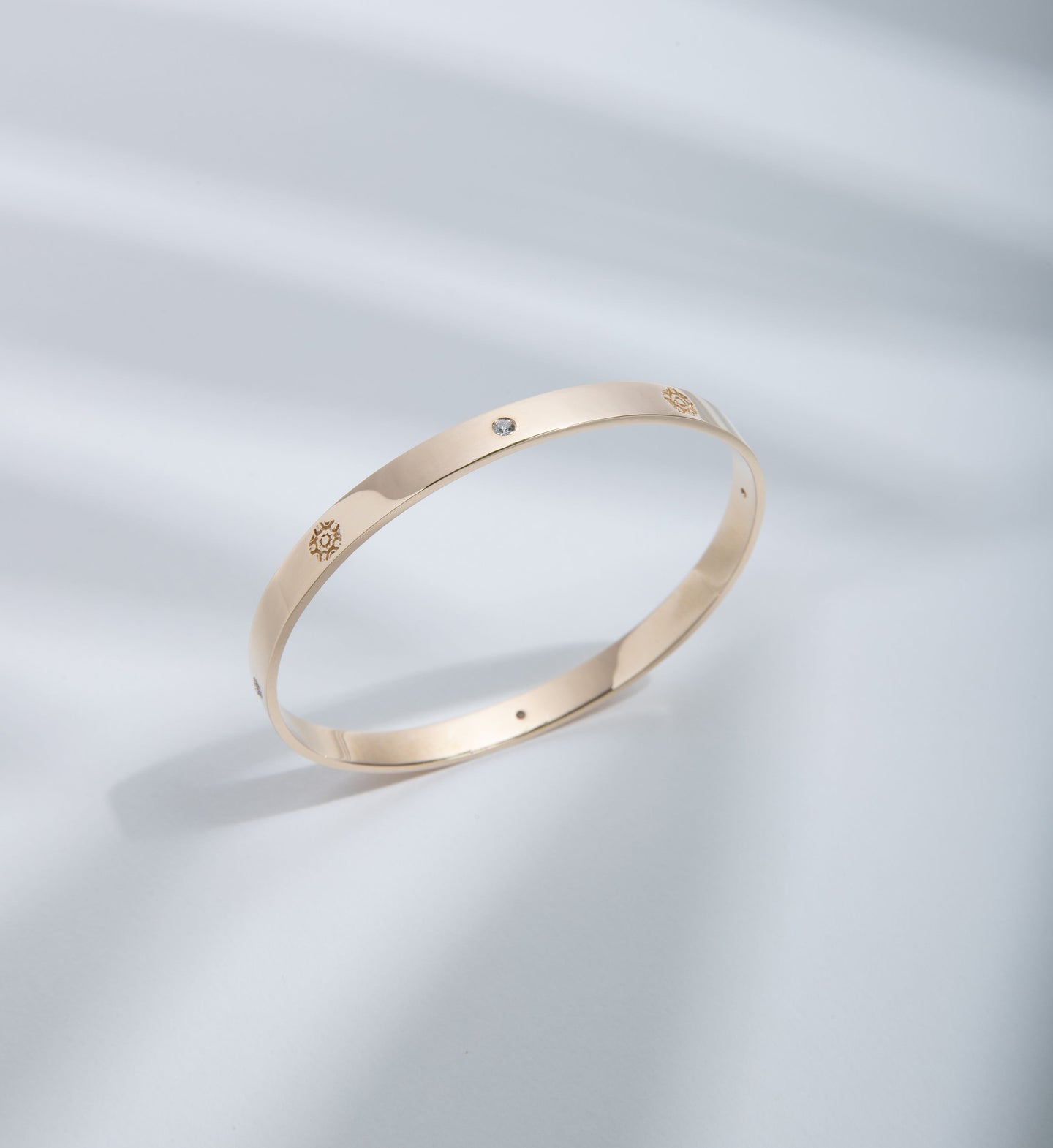 Hie Signature bangle bracelet in gold with logo engraving and diamond details, standing upright