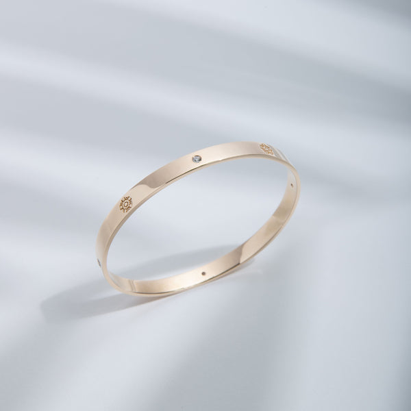 Hie Signature bangle bracelet in gold with logo engraving and diamond details, standing upright