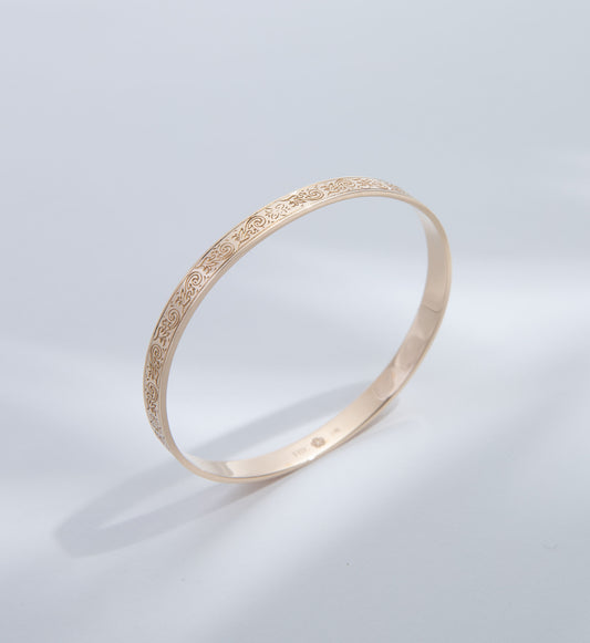 Hie Uluhe gold bangle bracelet with detailed engraving, standing upright