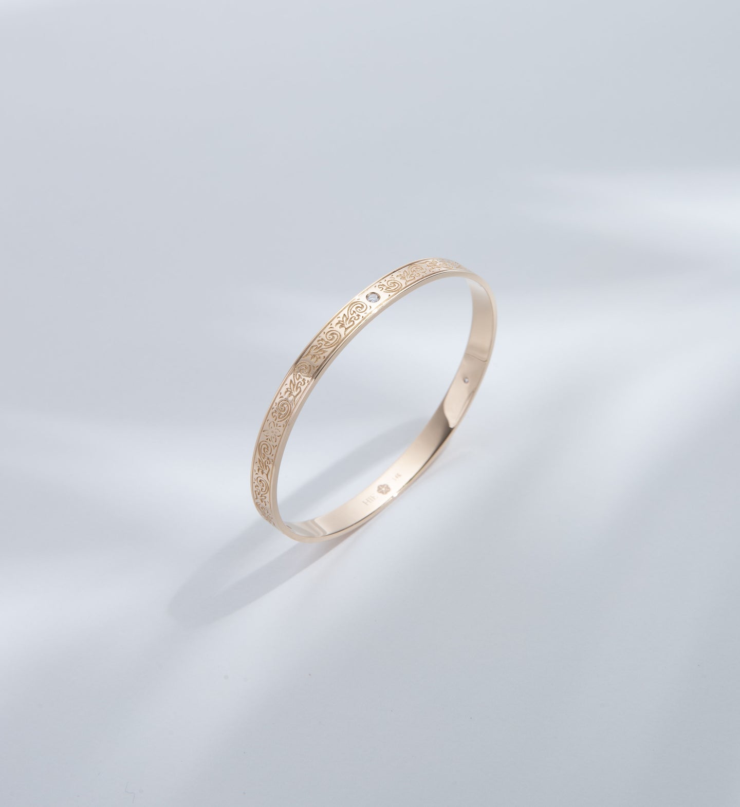 Hie Uluhe gold bangle bracelet with detailed engraving and diamonds, standing upright