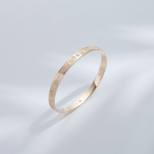 Hie Uluhe gold bangle bracelet with detailed engraving and diamonds, standing upright